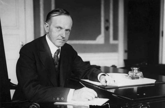 Valokuva Calvin Coolidgestä Valkoisen talon pöydällä.