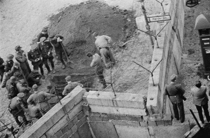 Ryhmä itäsaksalaisia ​​sotilaita tutkii Berliinin muurin alla kaivettua tunnelia.