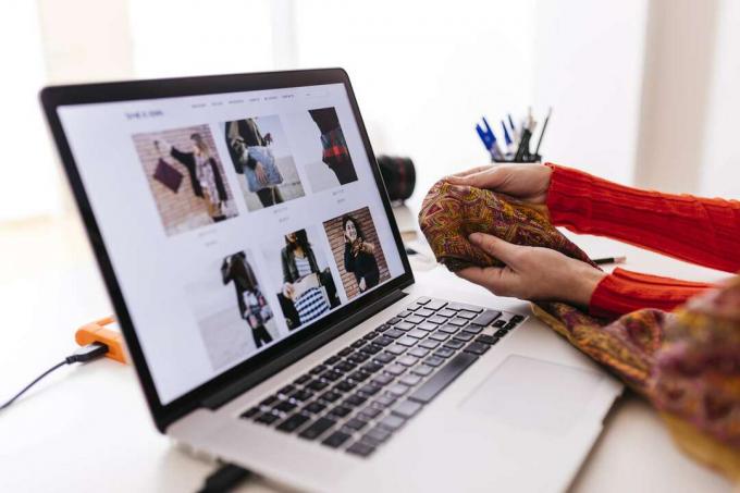 Nainen, jolla on kangas kannettavan tietokoneen edessä muotisivuston ollessa auki
