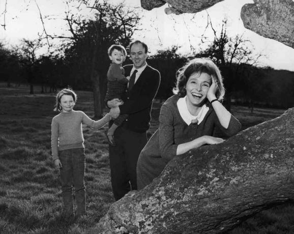 Mustavalkoinen valokuva Roald Dahlista, joka pitää lapsiaan; hänen vaimonsa Patricia Neal nojaa puuhun