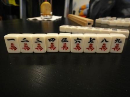 Hahmo puku joukosta Mahjong-laattoja istuu pöydällä.