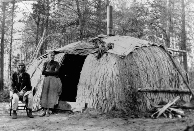 Ojibwa-pari wickiupinsa edessä.