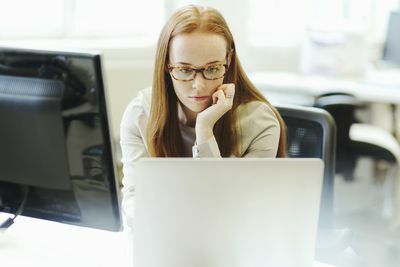 naispuolinen web-kehittäjä työskentelee tietokoneella