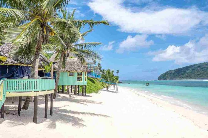 Näkymä Lalomanun rannalta, Upolu-saarella, Samoassa, värikkäistä samolaisrannikkojen fale-mökkeihin, jotka ovat vaihtoehto hotellille tai lomakohteelle
