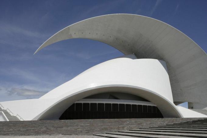 Kuva kirkkaanvalkoisesta modernista konserttisalista, jonka kaareva kaareva aalto katto yläpuolella.