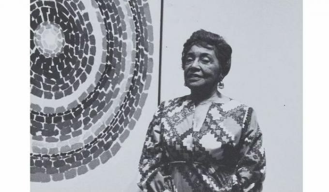 mustavalkoinen kuva Alma Thomasista yhden ympyrän abstraktioiden edessä