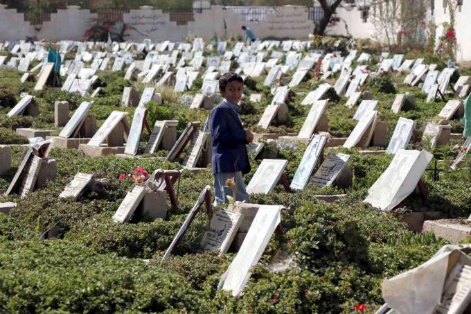 Lapsi kävelee meneillään olevassa sodassa kuolleiden hautojen keskuudessa Jemenin Sana'an hautausmaalla.