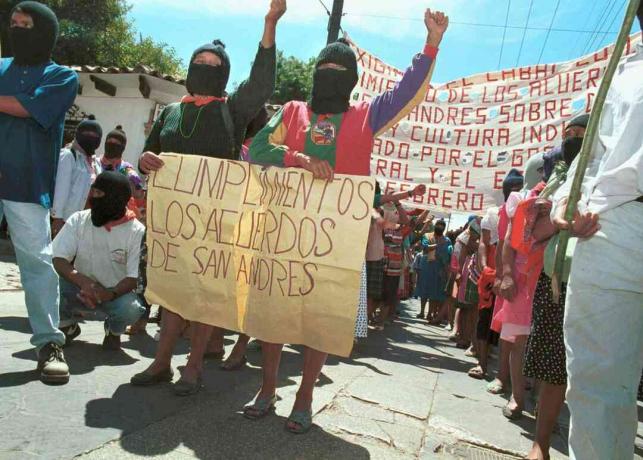 Kahdella naisella on kyltti, joka kehottaa hallitusta noudattamaan San Andrés -sopimusta