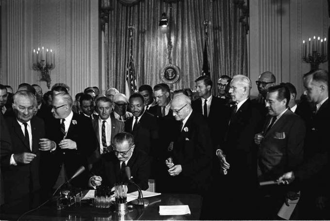 Presidentti Lyndon B. Johnson allekirjoittaa vuoden 1964 kansalaisoikeuslain, kun Martin Luther King, jr., ja muut katsovat.