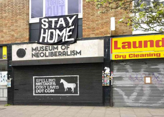 Suuri STAY HOME -kyltti suljetun uusliberalismin museon yläpuolella Lewsihamissa, Lontoossa, Englannissa.